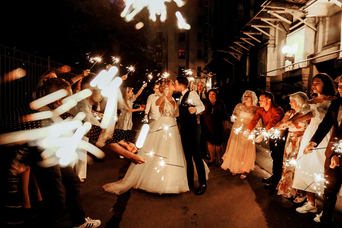 Newlywed couple kissing during wedding celebration in evening